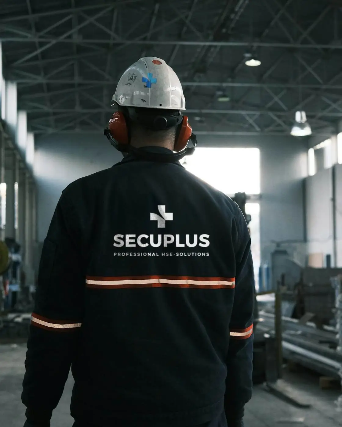 Fachkraft für Arbeitssicherheit mit SECUPLUS-Logo auf einer Industrieanlage